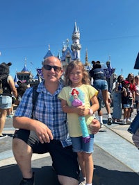 a man and a little girl posing for a photo in front of disneyland castle