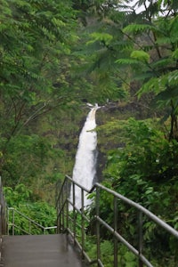 a waterfall is seen from a walkway in a forest