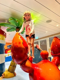 a little girl standing on top of a large crab