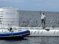 a man is standing next to a submarine in the ocean